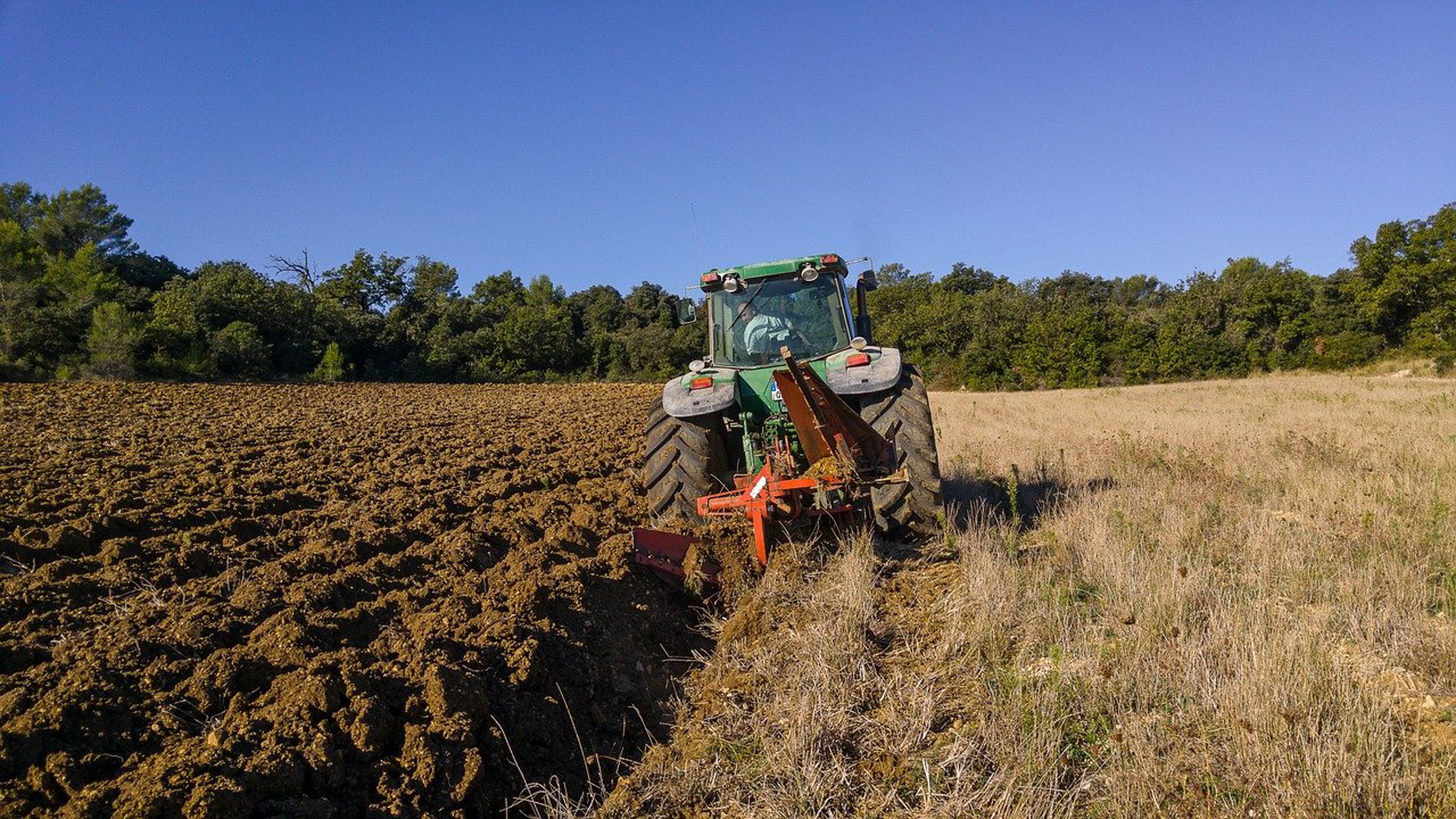 Traktor som pløyer et jorde. Foto.