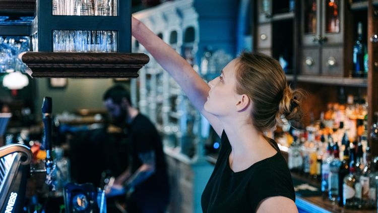 Bildet viser en kvinnelig servitør i en bar.