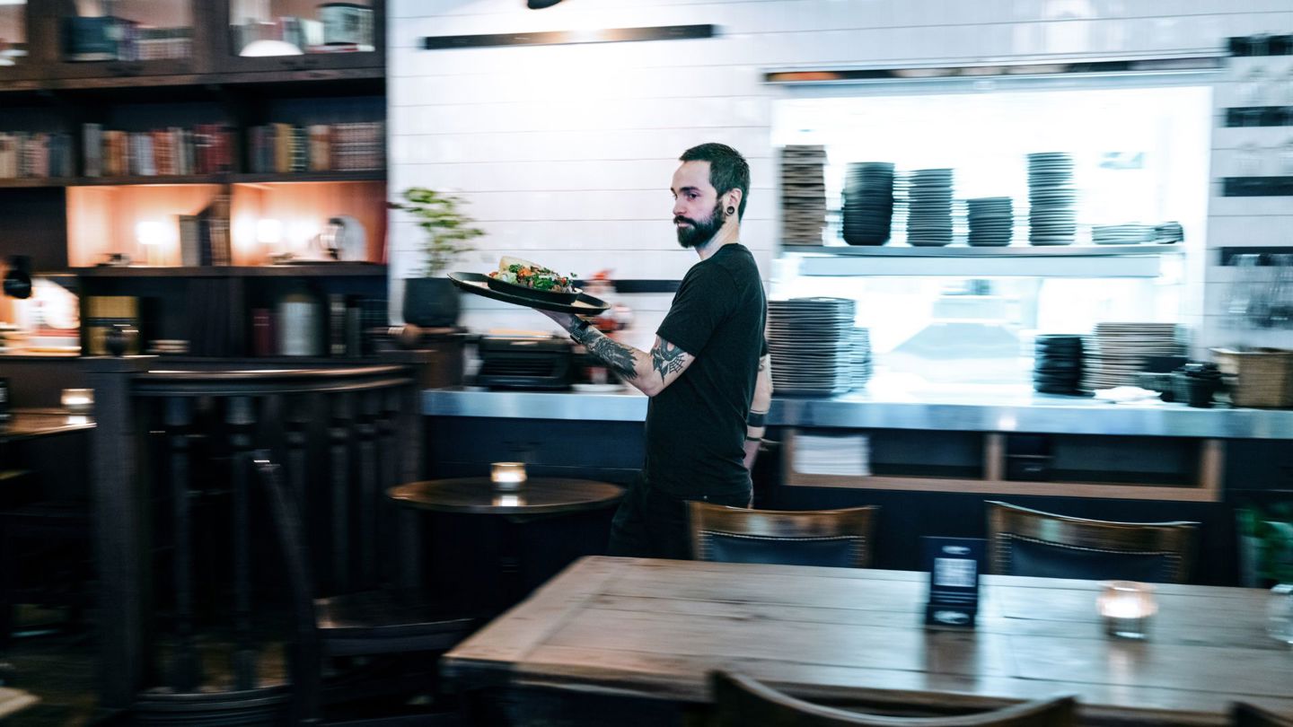 Bildet viser en mannlig servitør i en restaurant. 