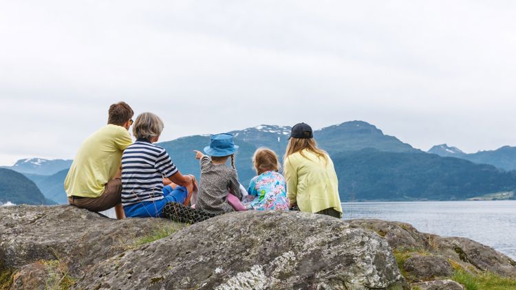Bildet viser en familie som ser utover fjord og fjell. 